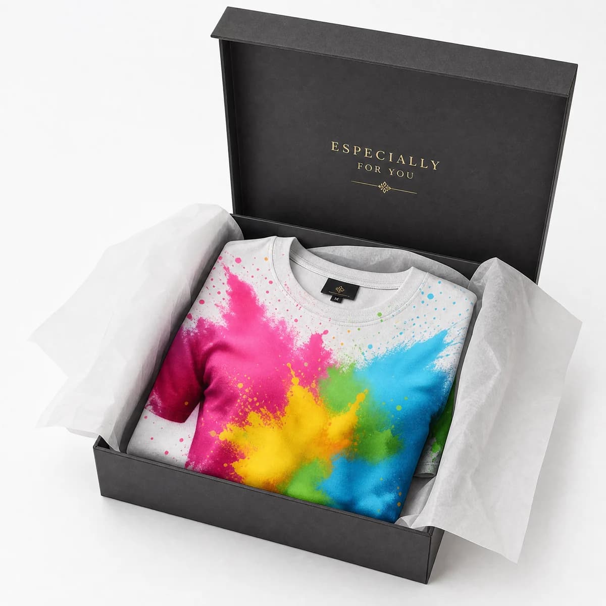 Color-splatter T-shirt folded in an open black gift box with white tissue paper and small English gift wording