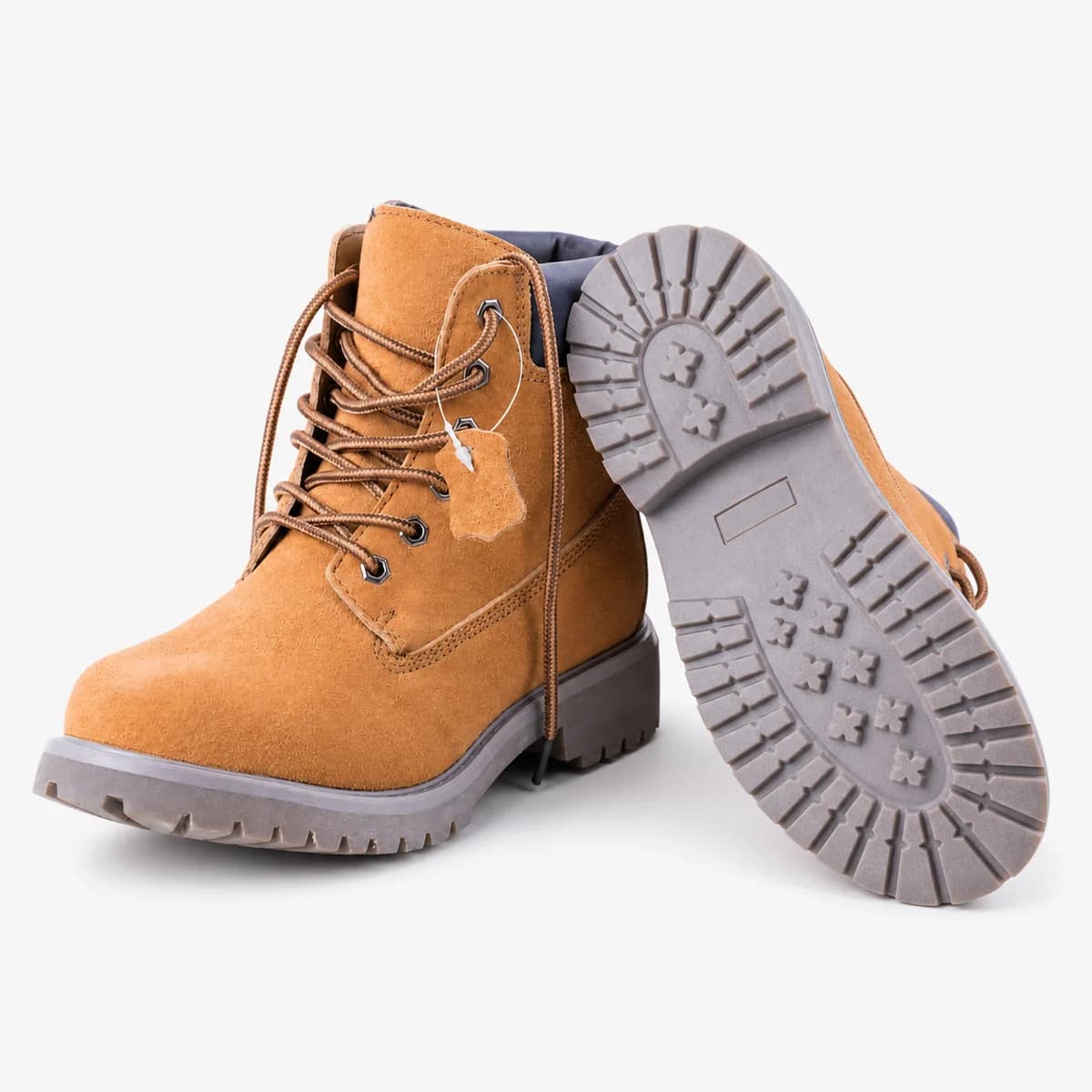 Tan hiking boots on a white background, with one boot turned to reveal the sole tread
