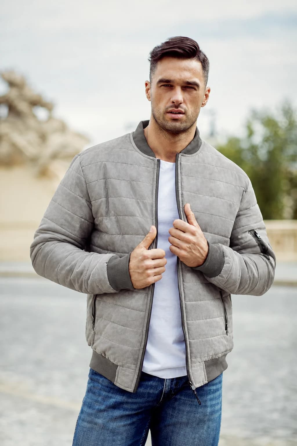 Male model wearing a grey quilted jacket in the same outdoor composition