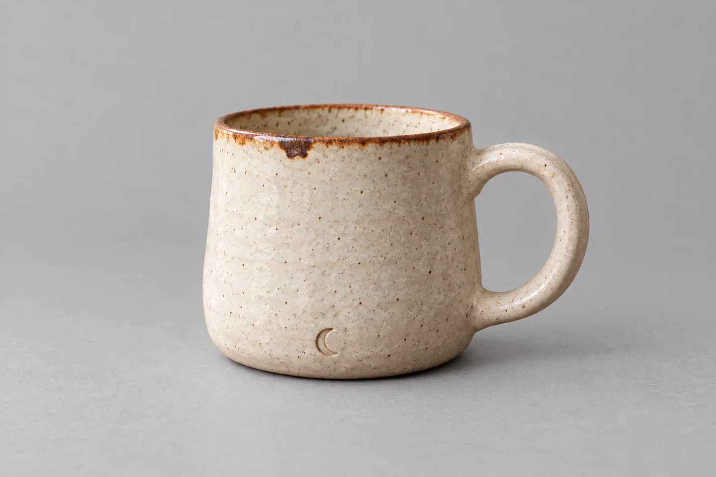 Edited mug on a light-gray backdrop with the oval handle, brown rim patch, and crescent mark still visible