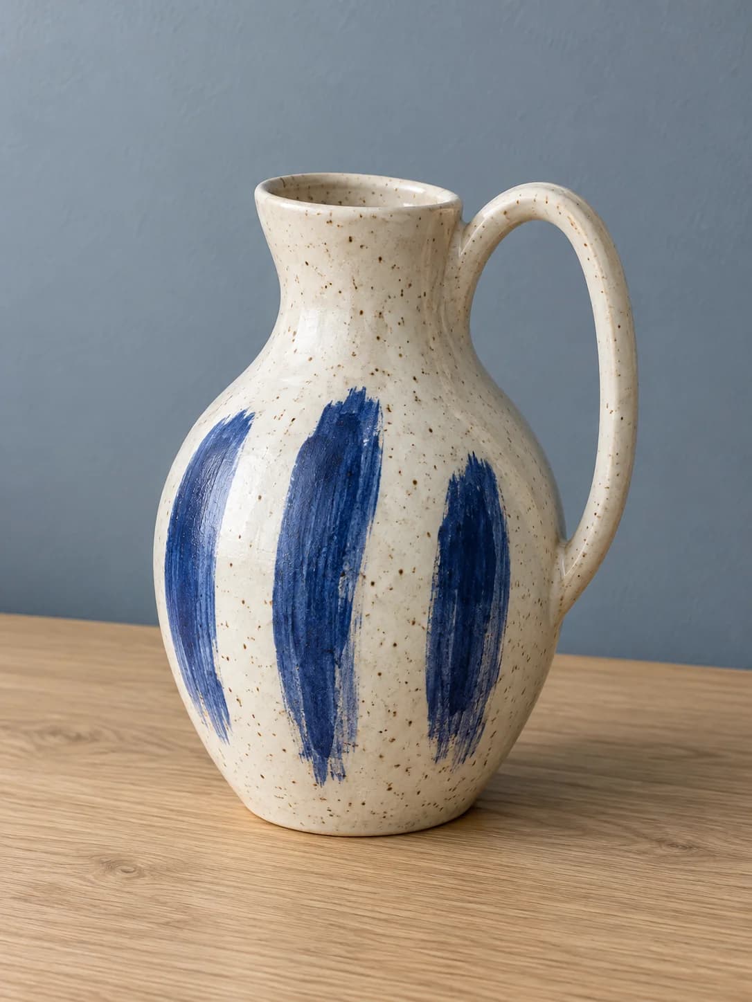 Ivory handled vase with cobalt brush marks on an oak table against a blue-gray wall